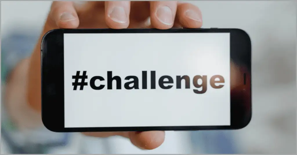 A person holding a phone displaying the word 'Challenge,' symbolizing overcoming obstacles using Sphere of Influence strategies in real estate.