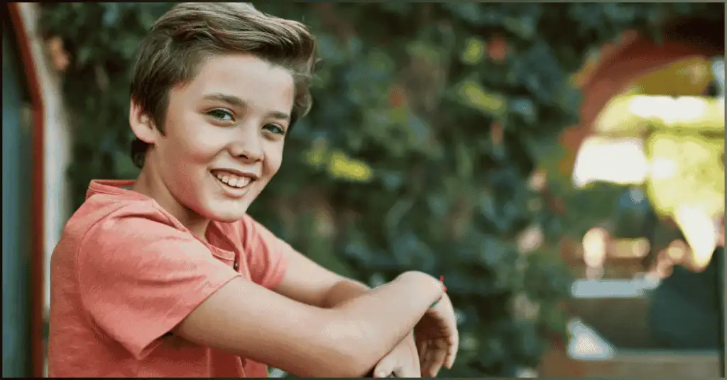 Boy smiling at his house grill, captured in natural light using the Best Shutter Speed for Portraits.
