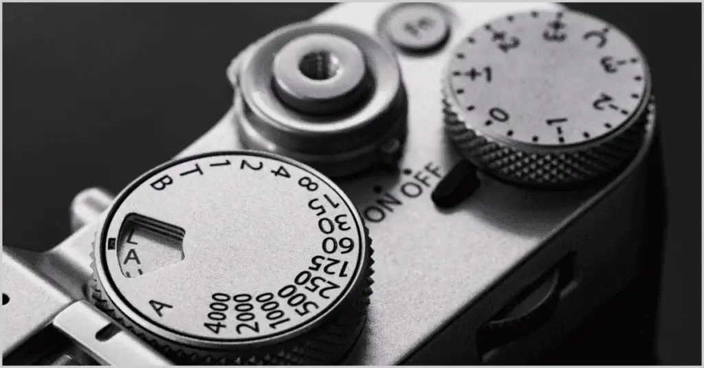 Close-up of a camera's round shutter button, highlighting the connection between shutter speed and lens focal length.