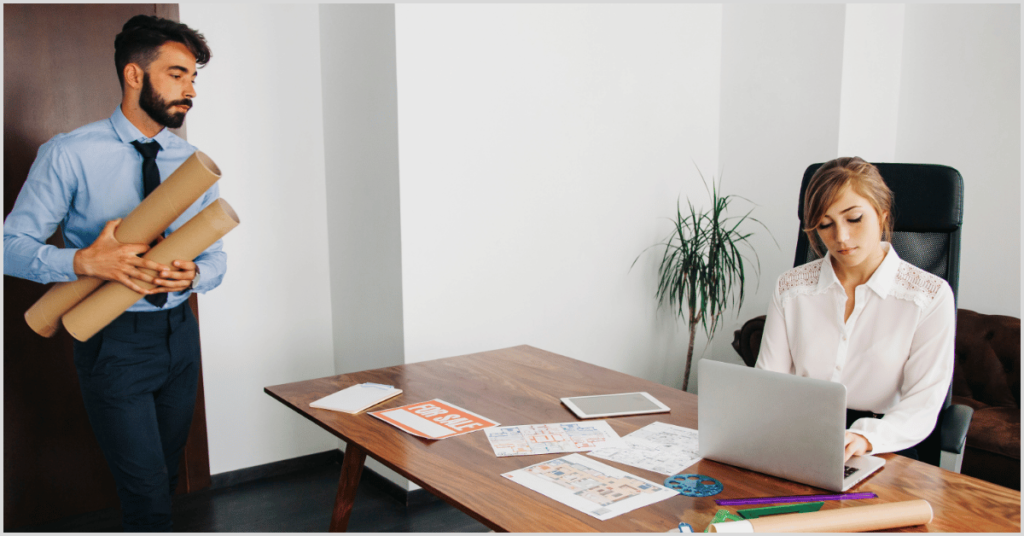 A man holding blueprints and a woman working on a laptop with real estate documents, symbolizing partnership with home builders.