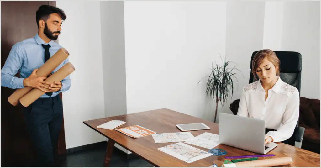 A man holding blueprints and a woman working on a laptop with real estate documents, symbolizing partnership with home builders.