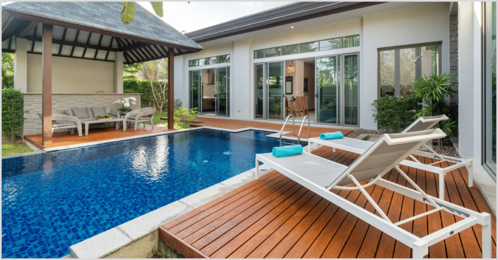 Modern house with a blue pool, wooden deck, lounge chairs, and outdoor seating area.A contemporary house featuring a vibrant pool, wooden deck with lounge chairs, and an outdoor seating area, raising the question of selling difficulty.