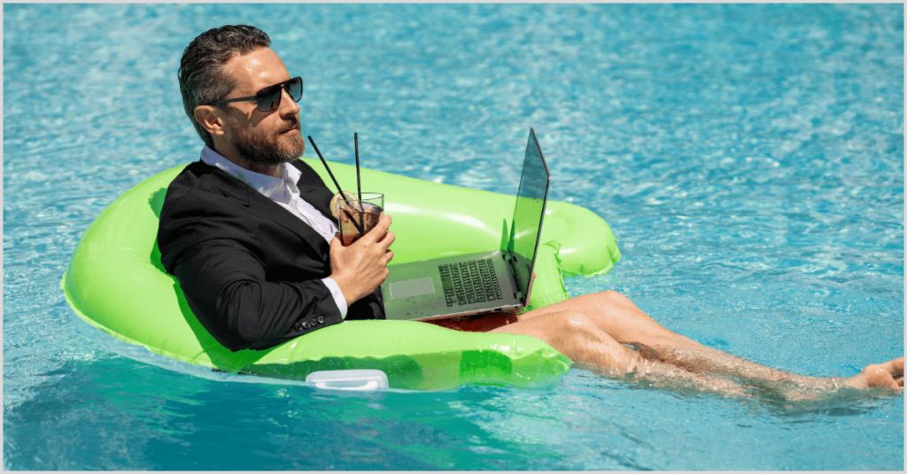 Man in a suit working on a laptop while relaxing on a pool float.