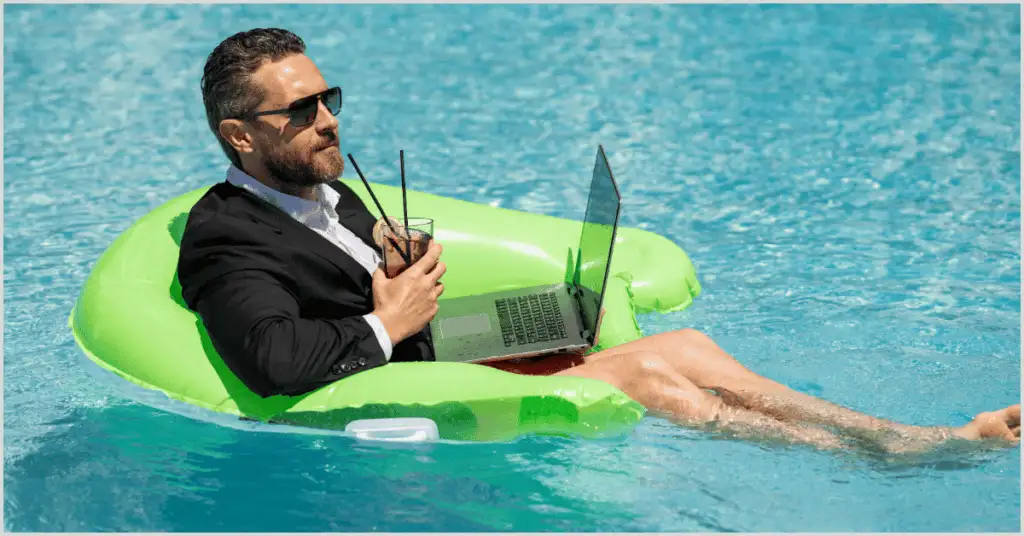 Man in a suit working on a laptop while relaxing on a pool float.