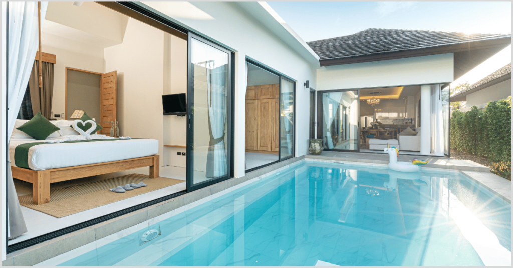 Luxurious bedroom with open glass doors leading to a private pool, featuring a unicorn float.