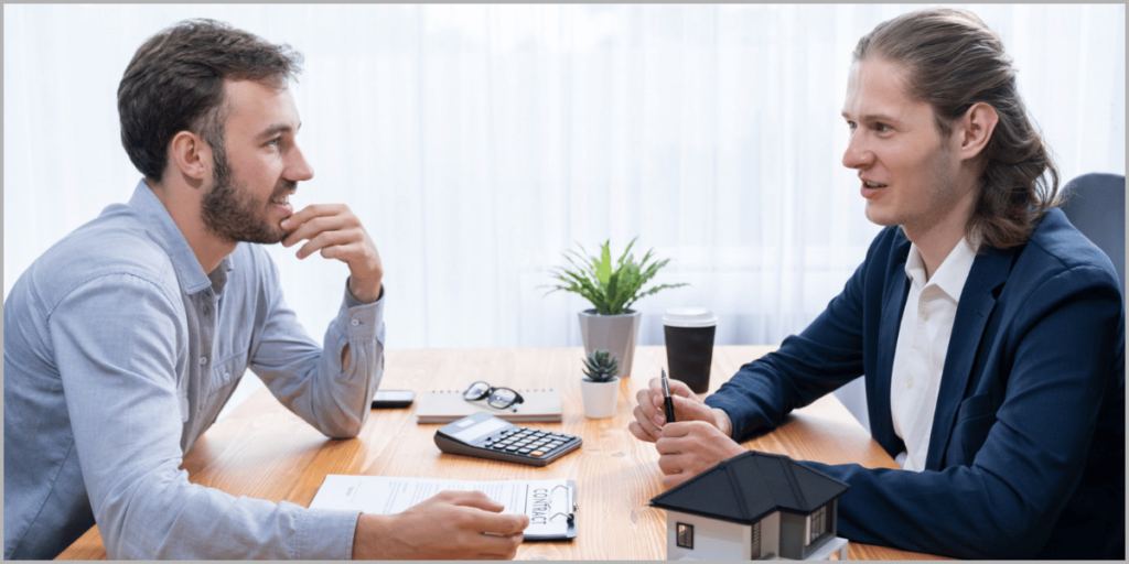 Two professionals discussing real estate contract at a table with a house model.