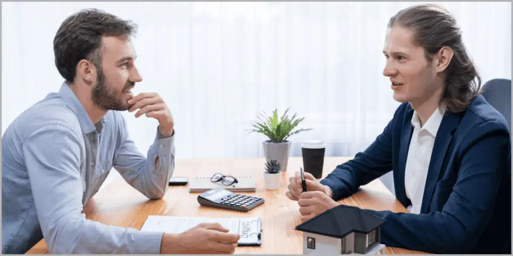 Two professionals discussing real estate contract at a table with a house model.