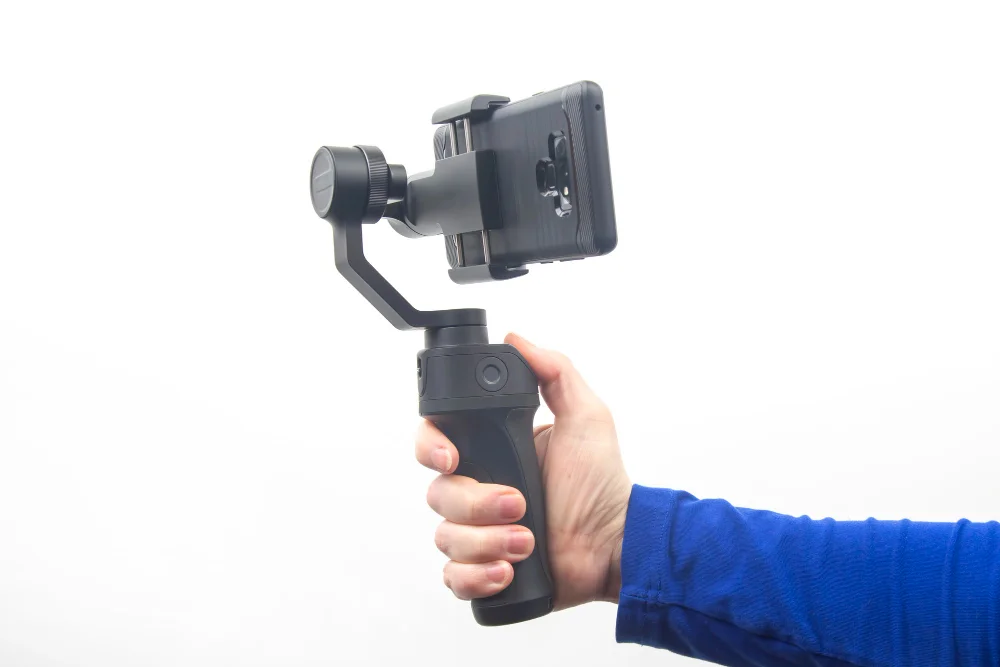 Hand holding a compact 3-axis smartphone gimbal with phone mounted, demonstrating proper grip technique for advanced smooth shots – how to use a gimbal.