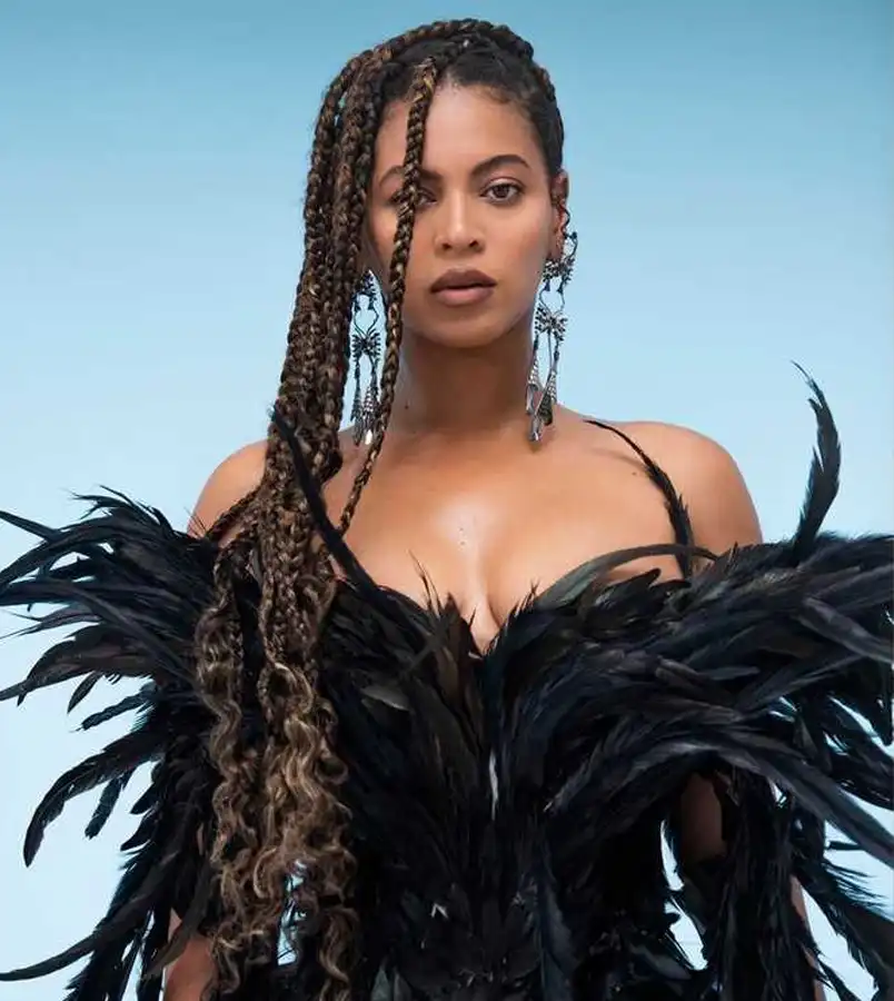 Beyoncé in dramatic black feathered outfit with long braids and fierce expression, iconic portrait – Who Is The Most Photographed Person In The World