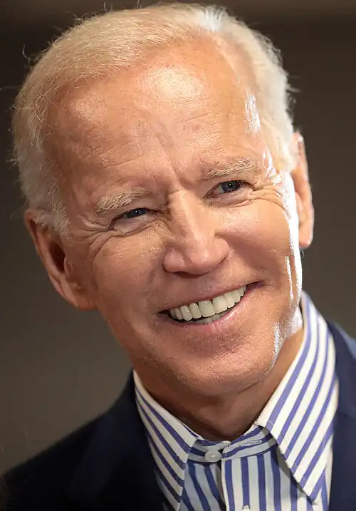 Joe Biden smiling warmly in blue striped shirt and dark blazer, close-up portrait – Who Is The Most Photographed Person In The World