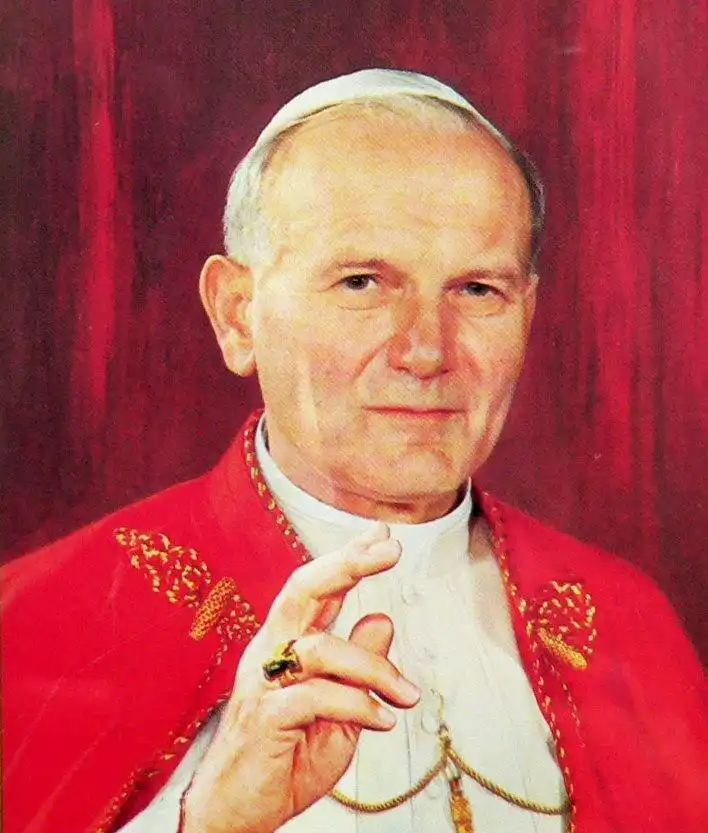 Pope John Paul II in red papal vestments and white zucchetto, gesturing with hand, thoughtful expression – Who Is The Most Photographed Person In The World