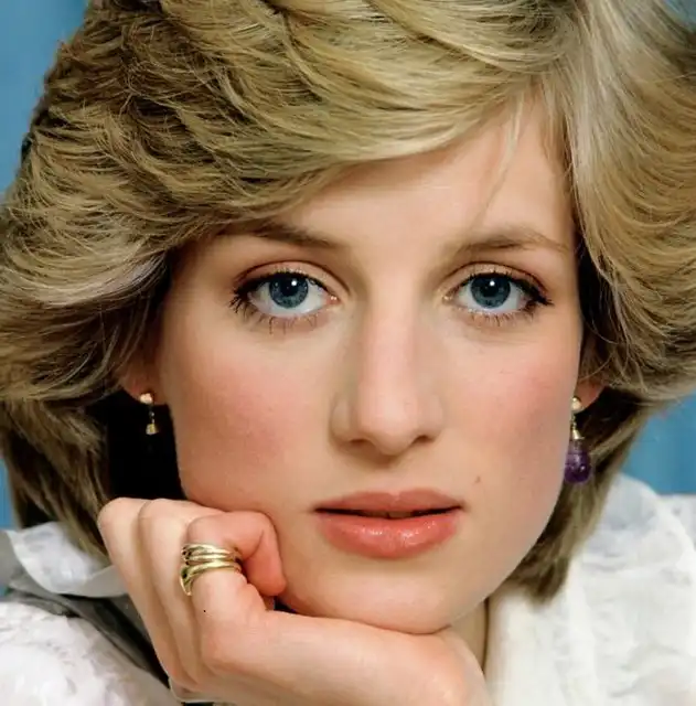Princess Diana in a timeless close-up portrait with blonde wavy hair, blue eyes, and elegant jewelry, gazing directly at the camera – Who Is The Most Photographed Person In The World