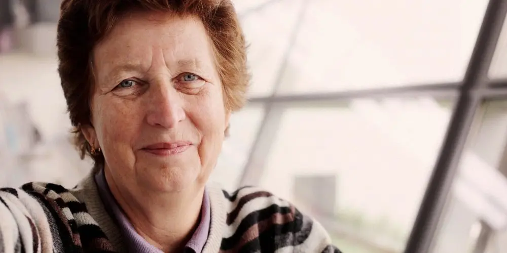 Close-up portrait of an older woman with natural wrinkles and soft smile in natural light, showing Realism in Photography